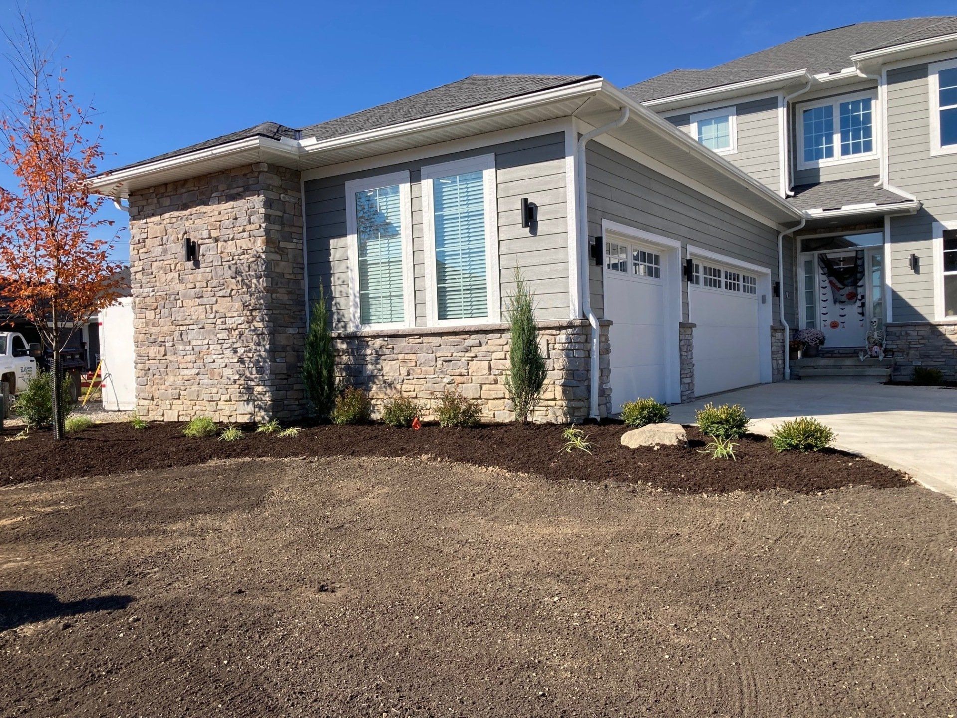 Suburban house exterior with stone facade, garage, and a newly graded front yard