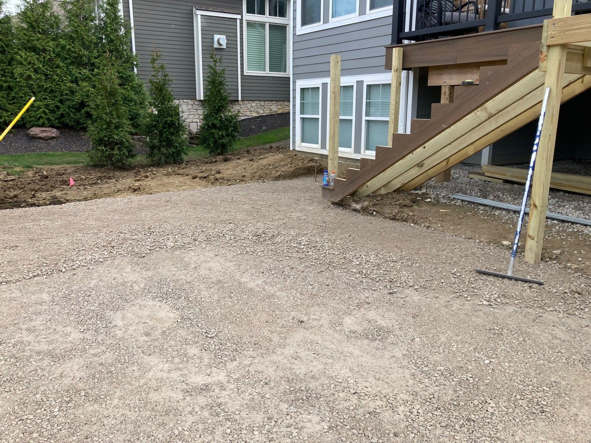 Gravel driveway beside a house with a wooden ramp and stairs leading to a side entrance.