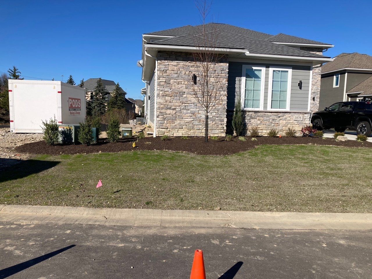 Suburban house with stone facade, front lawn, and a white utility box near the curb.