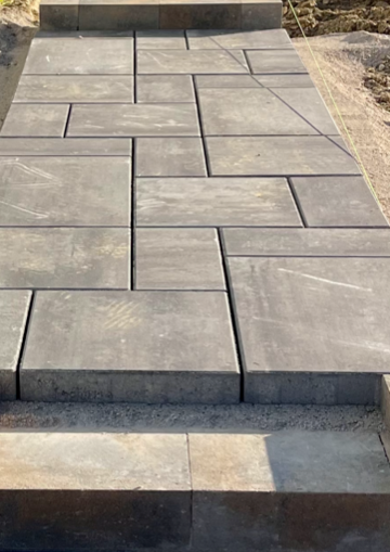 Gray concrete pavers laid in a staggered pattern on a small outdoor walkway with steps.