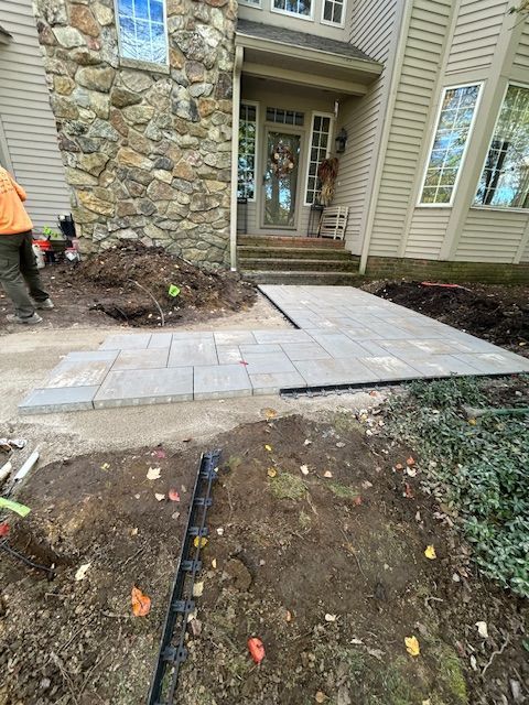 Stone front entry with new concrete walkway and surrounding dirt landscaping under construction