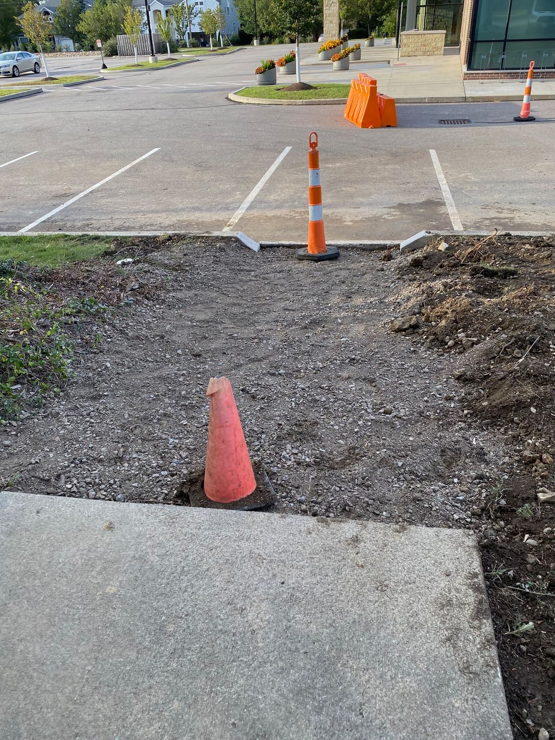 Orange traffic cones blocking a gravel cut-through between parking spaces