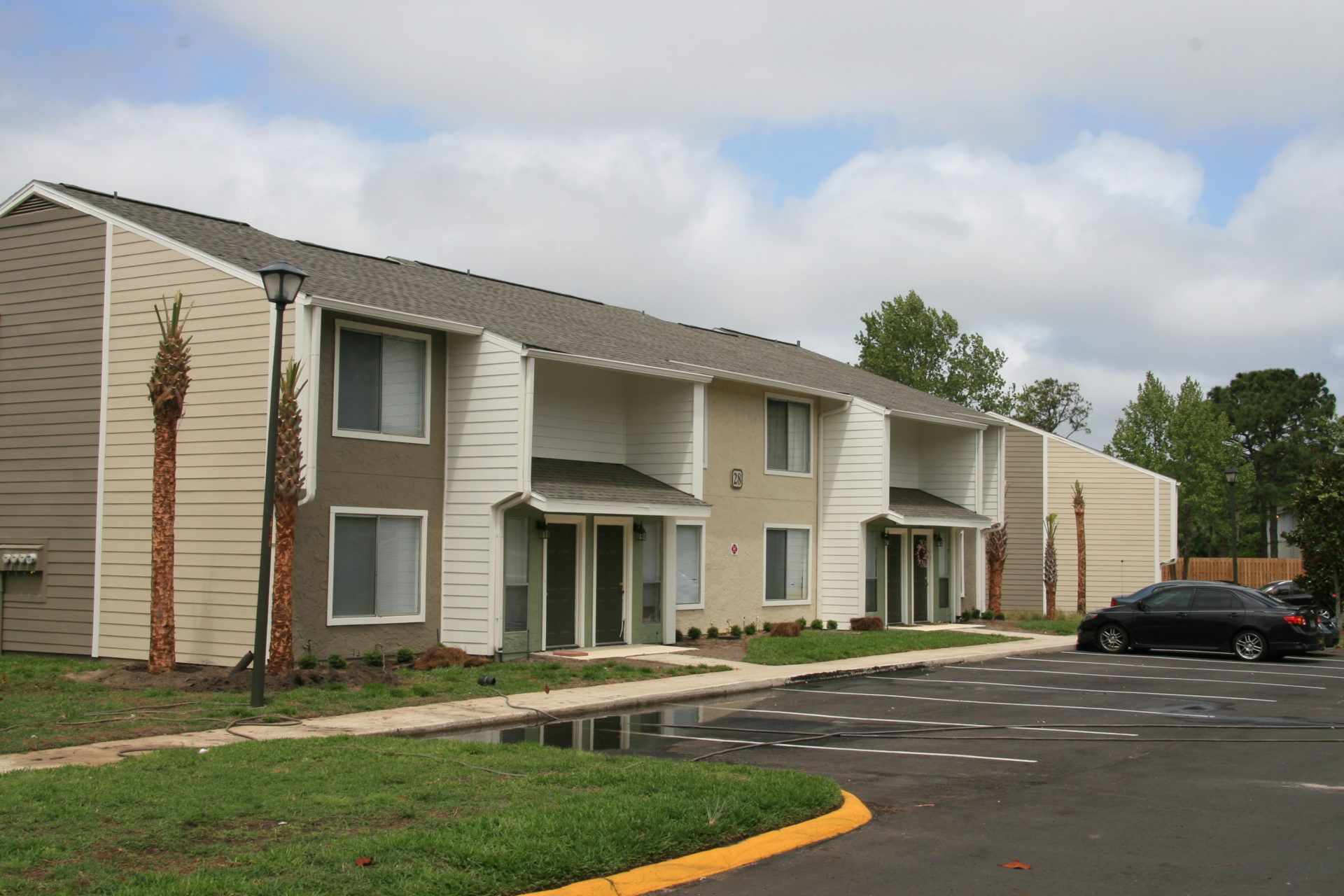 Apartment complex exterior with beige siding, balconies, and a parking lot in front