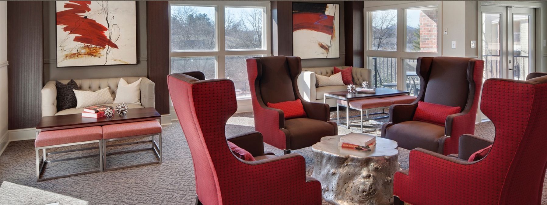 Modern living room with red chairs, a sofa, coffee table, fireplace, and large windows