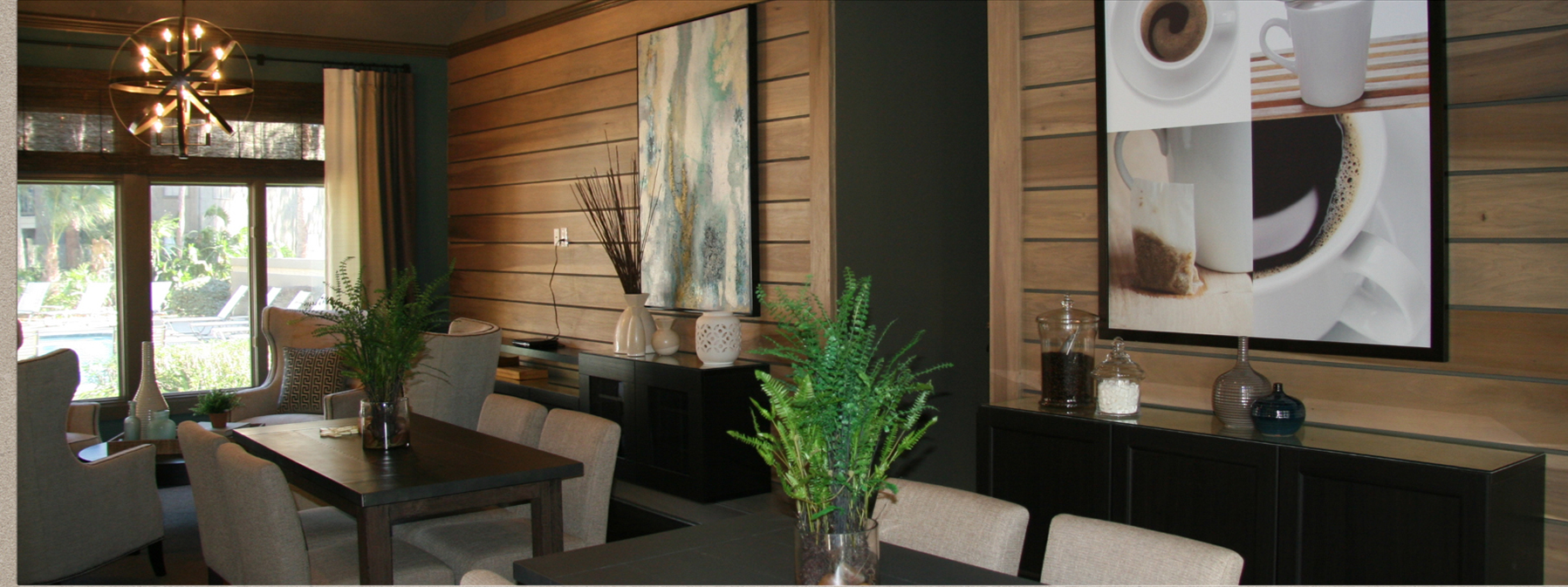 Modern lobby lounge with wood-paneled walls, black seating, potted plants, and framed artwork