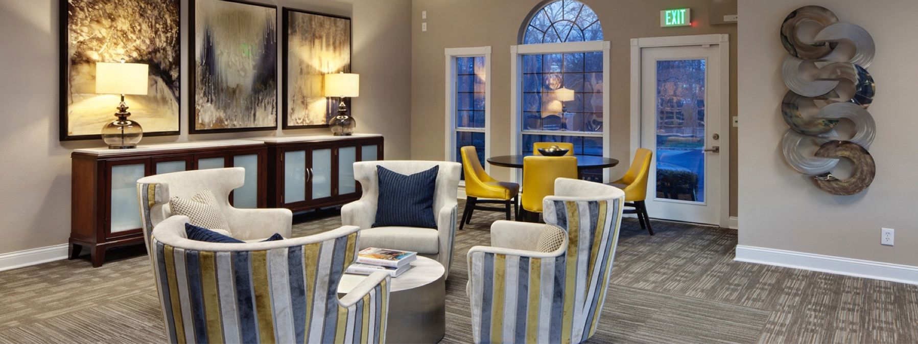 Lobby seating area with striped chairs, dark console tables, and arched glass doors at the back