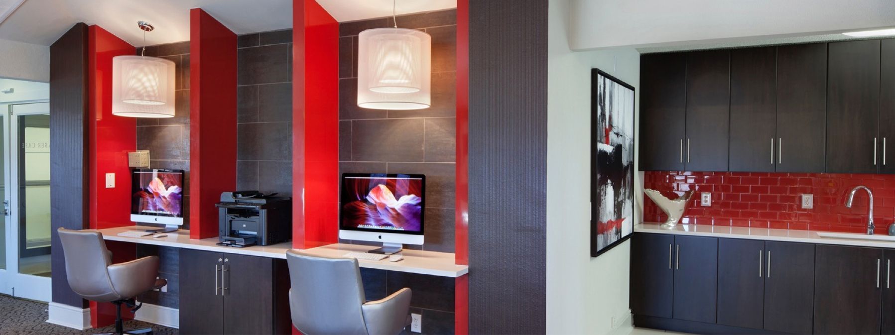 Modern kitchen with red backsplash, dark cabinets, island seating, and contemporary pendant lights