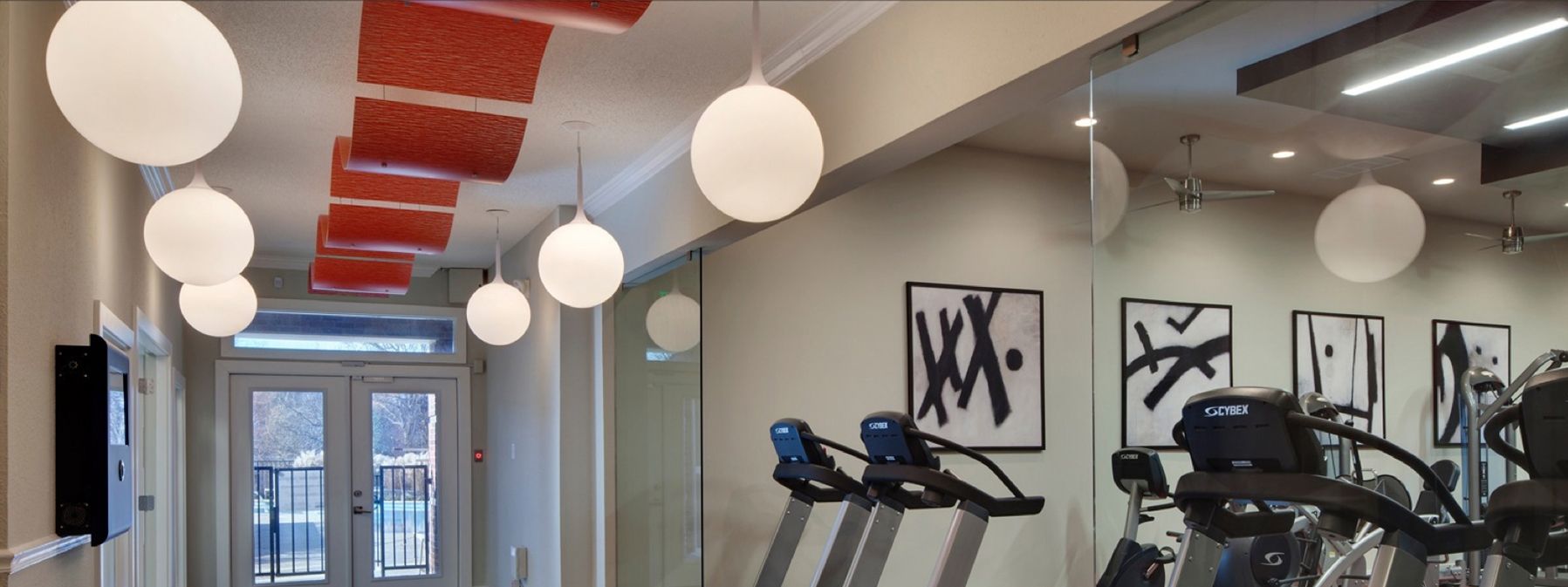 Modern gym interior with treadmills, wall art, and hanging globe lights