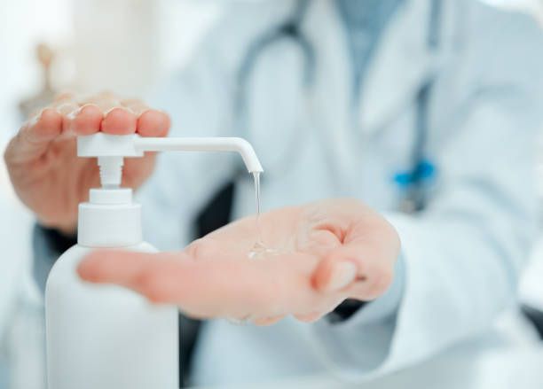 Un médico le está aplicando desinfectante para manos.
