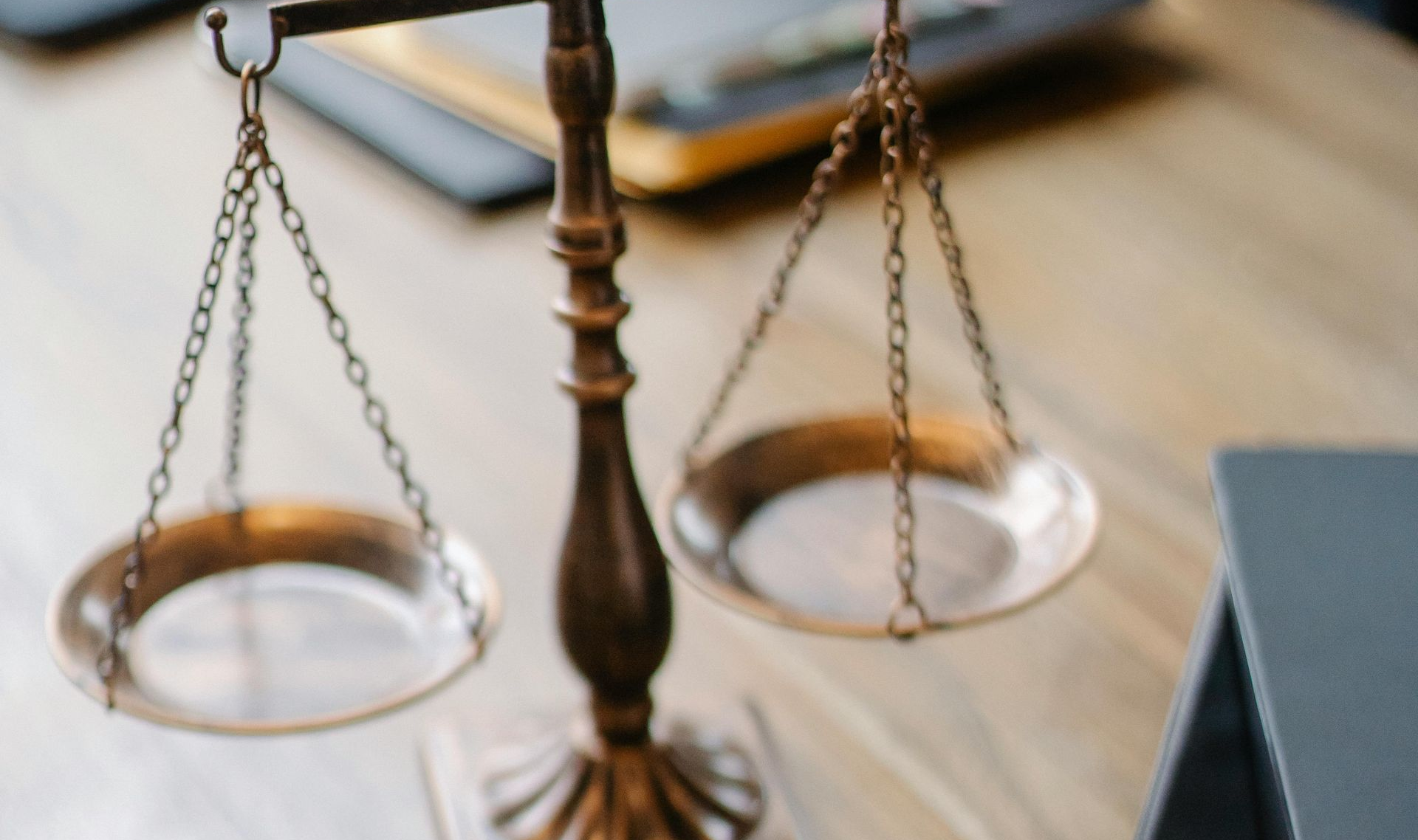 Scales of justice, bronze colored, on a wooden table, empty trays.