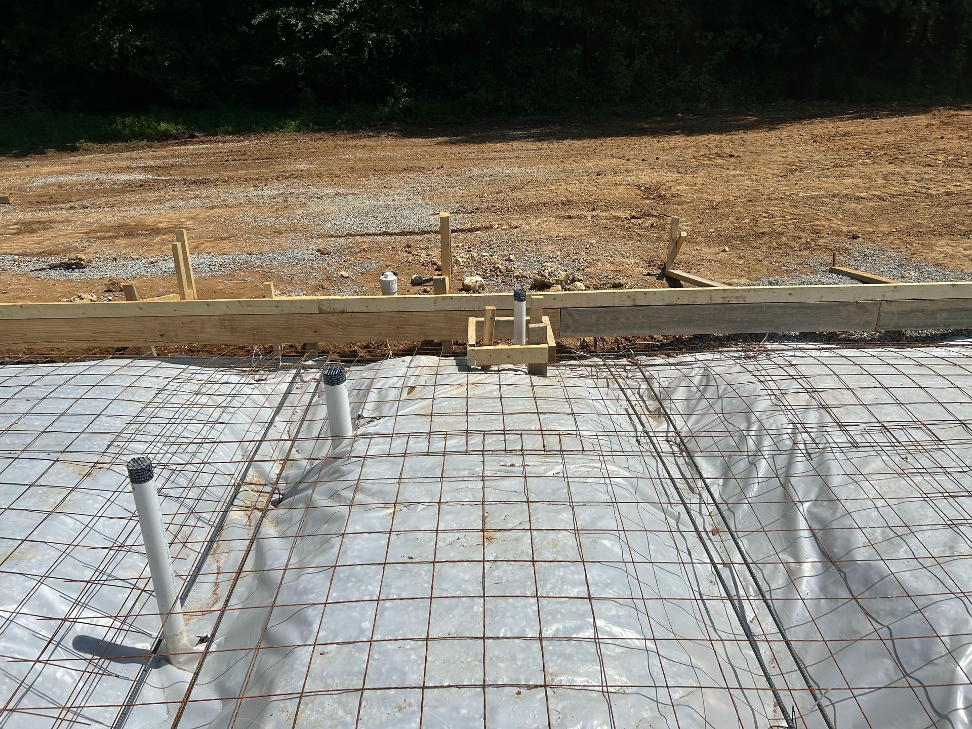 A concrete foundation is being built in a dirt field
