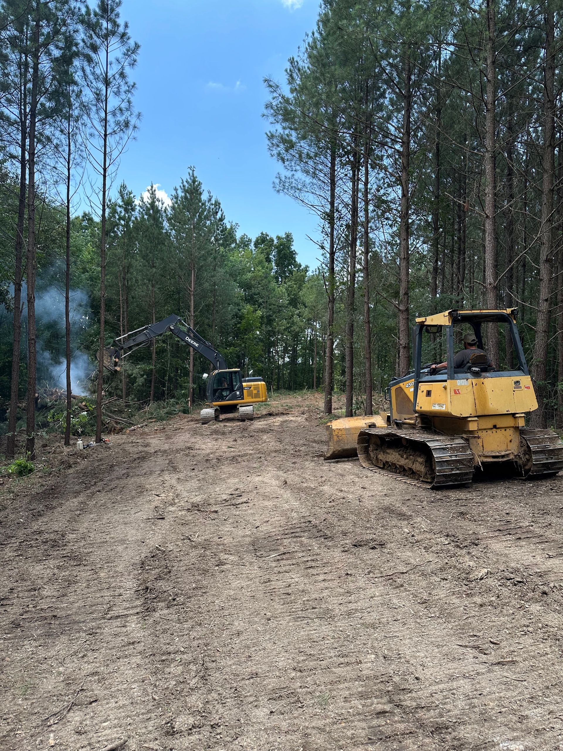 A couple of bulldozers are sitting in the middle of a forest.