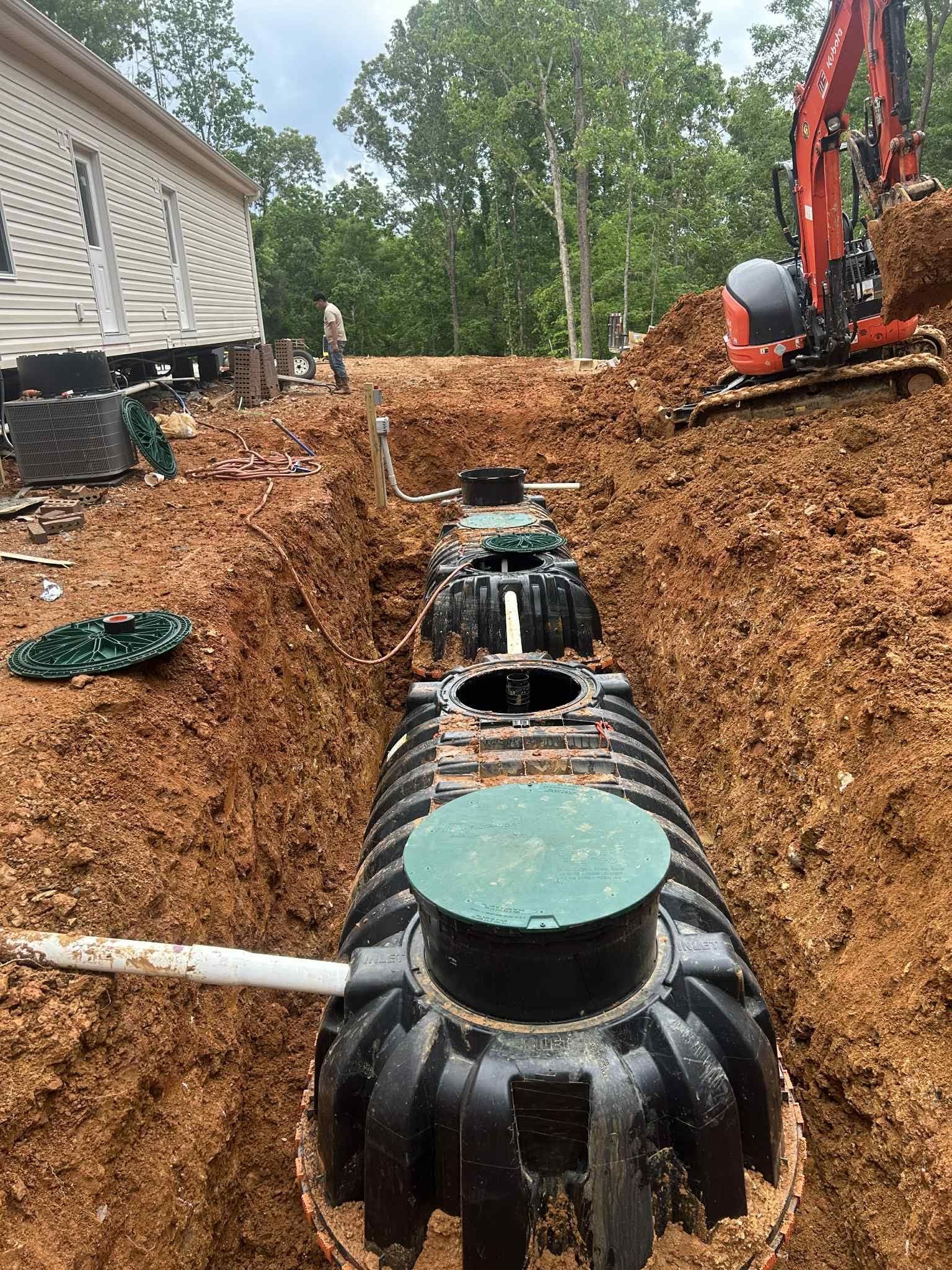 A septic tank is being installed in the dirt next to a house.