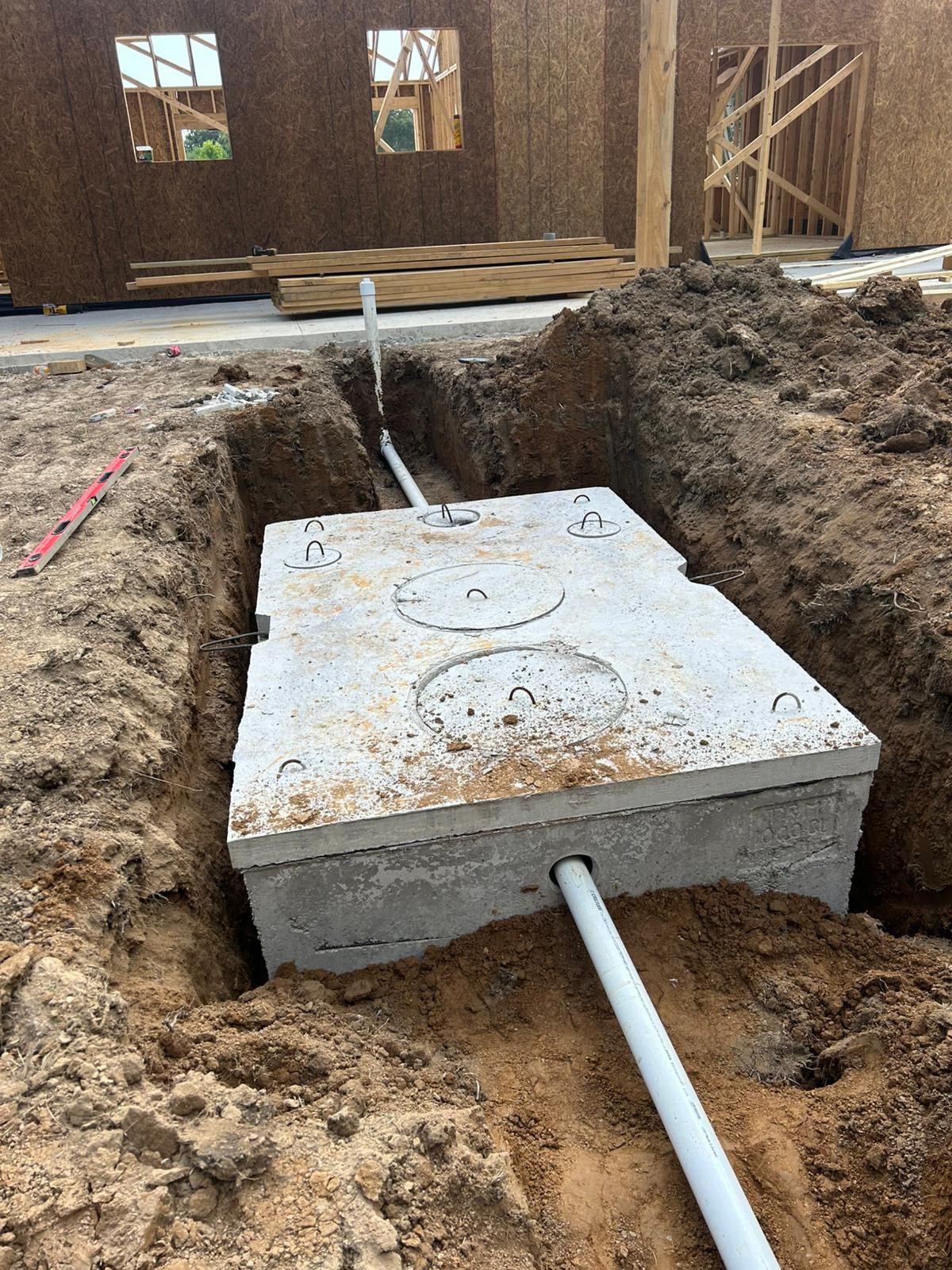A septic tank is being installed in the dirt next to a house.