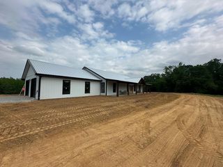 A concrete foundation is being built in a dirt field with trees in the background.