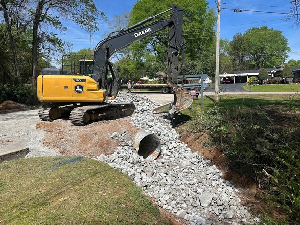 A man is kneeling in the dirt in front of a concrete mixer truck.