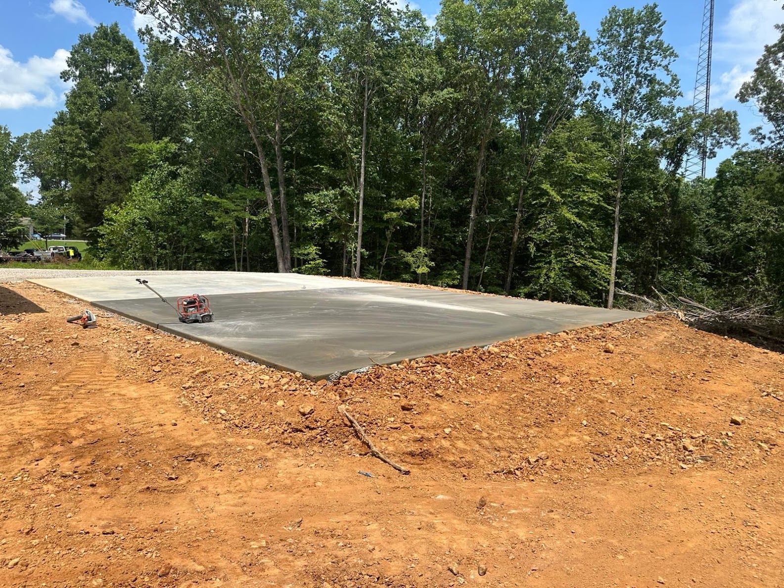 A concrete slab is sitting in the middle of a dirt field surrounded by trees.