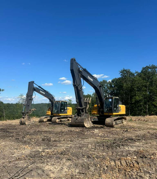 A couple of bulldozers are sitting in the middle of a forest.