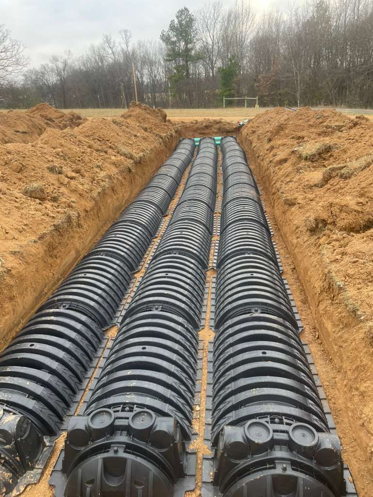 A septic tank is being installed in the dirt next to a house.