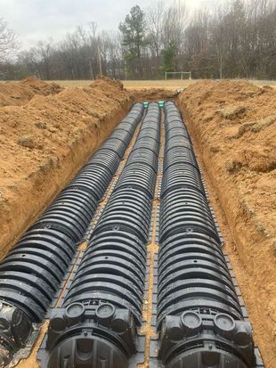 A septic tank is being installed in the dirt next to a house.