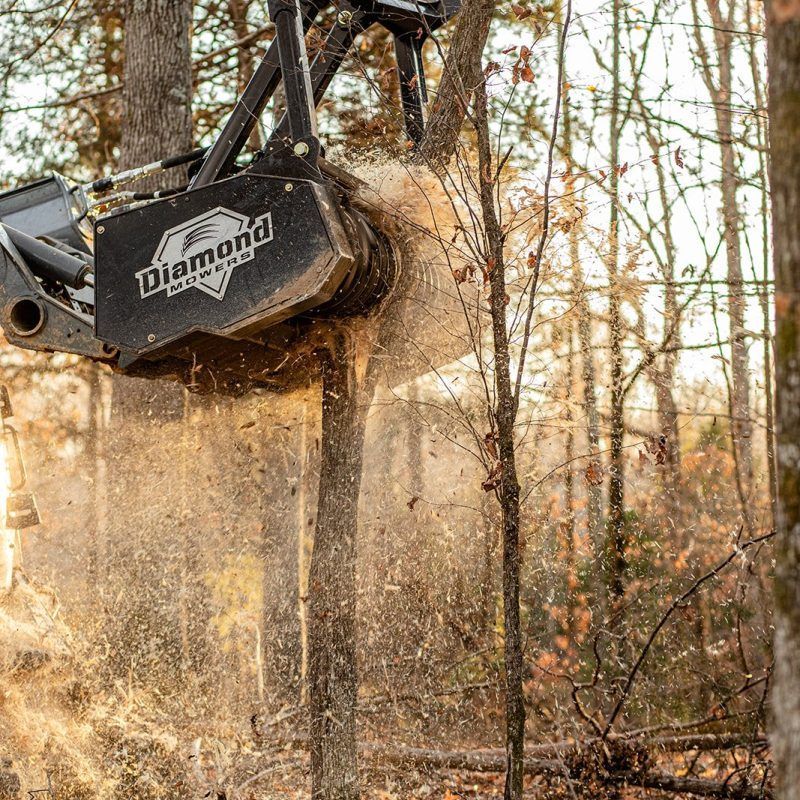 A machine is cutting a tree in the woods.