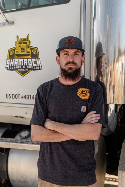A man with a beard is standing in front of a shamrock truck