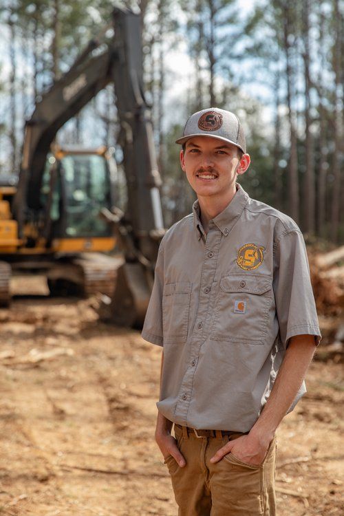 A man is standing in front of a bulldozer in a field.