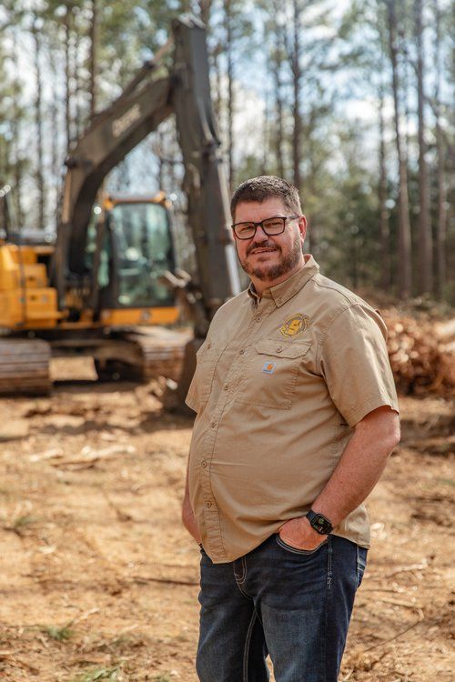 A man is standing in front of a bulldozer in a field.