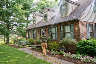 Residential pest control technician inspecting home baseboard