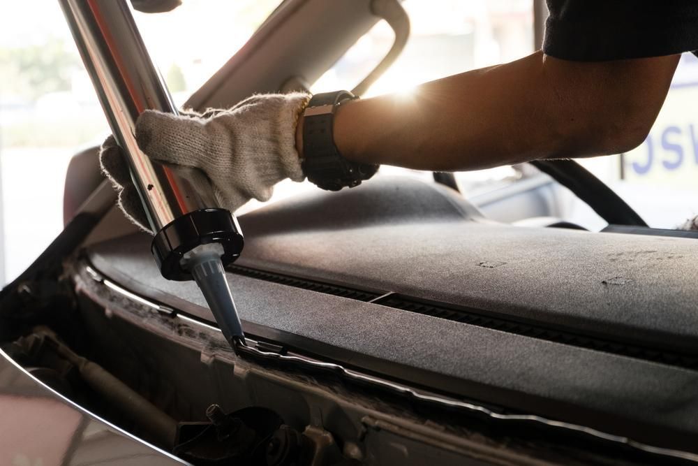 A Man Is Installing A Windshield On A Car — Windscreen Ambulance In Kawana, QLD