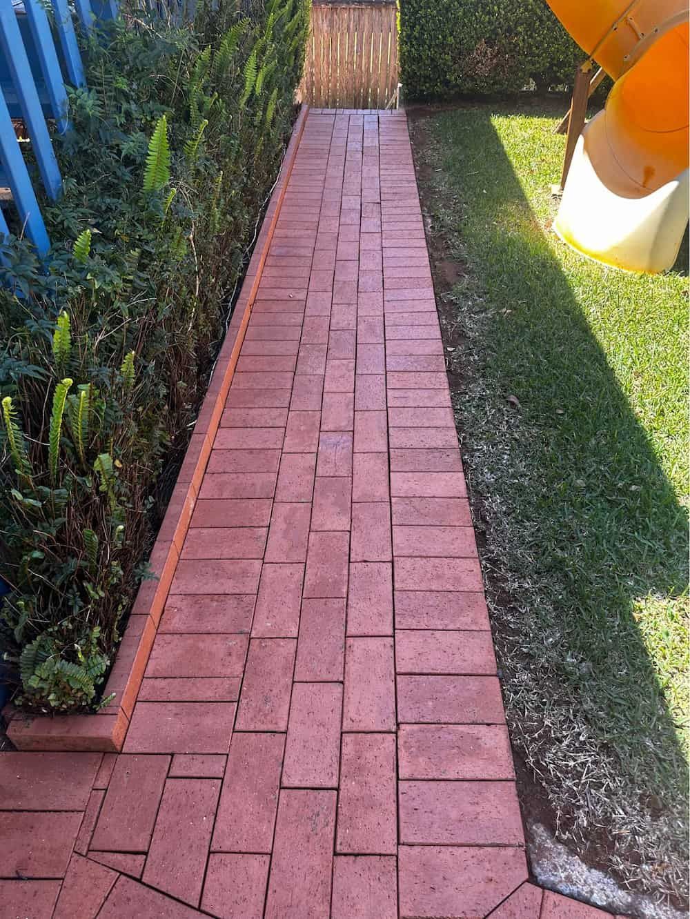A Red Brick Walkway Leading to a Slide in a Backyard — Lighthouse pressure washing in Port Macquarie, NSW