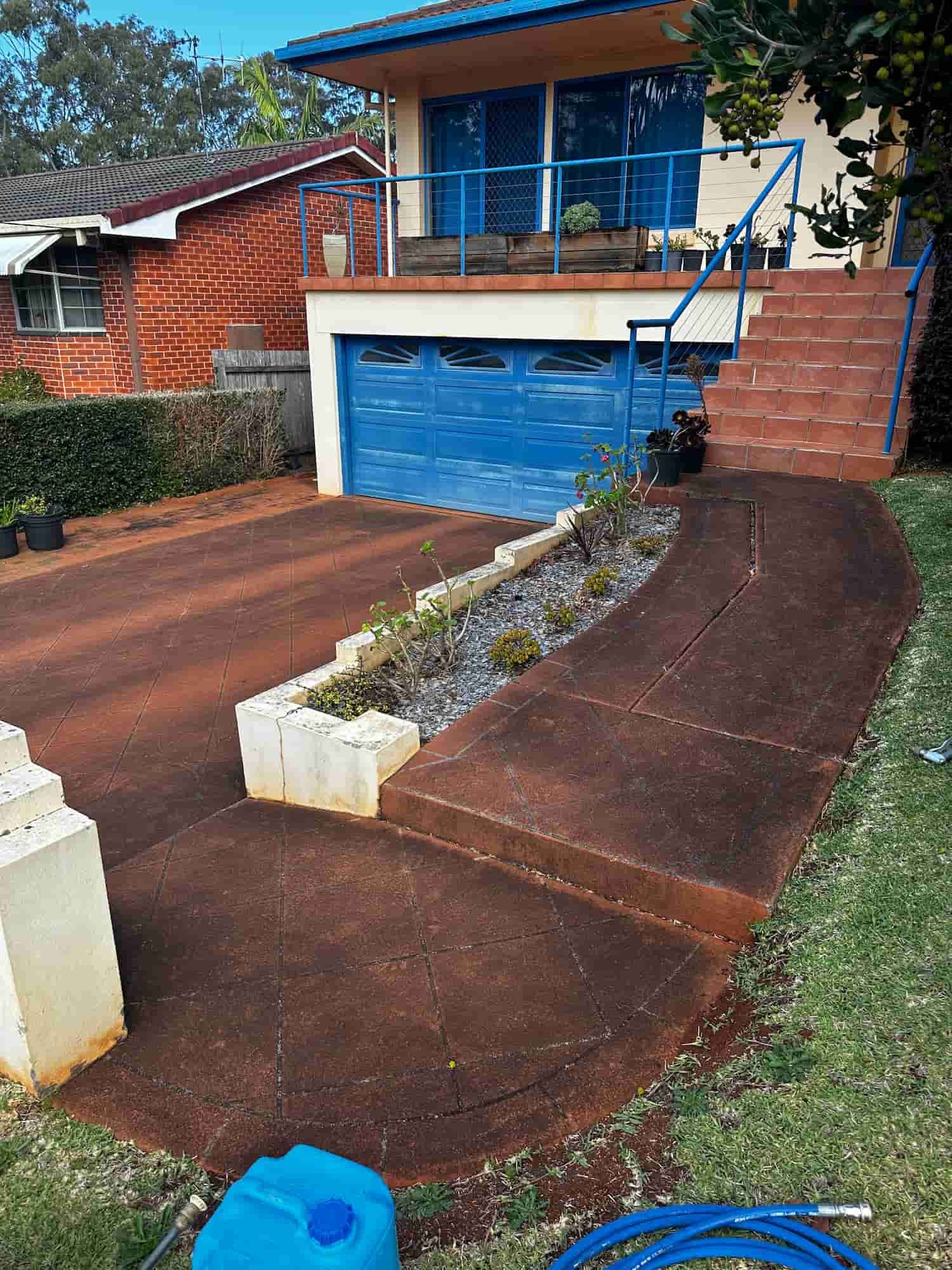 A Concrete Walkway Leading to a House With a Blue Garage Door — Lighthouse pressure washing in Thrumster, NSW
