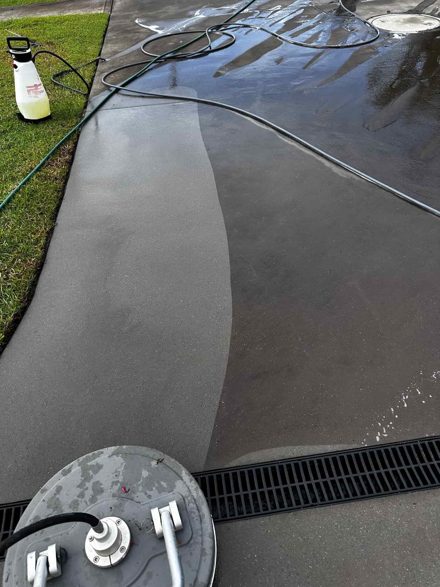 A Concrete Driveway is Being Cleaned With a Pressure Washer — Lighthouse pressure washing in Bonny Hills, NSW