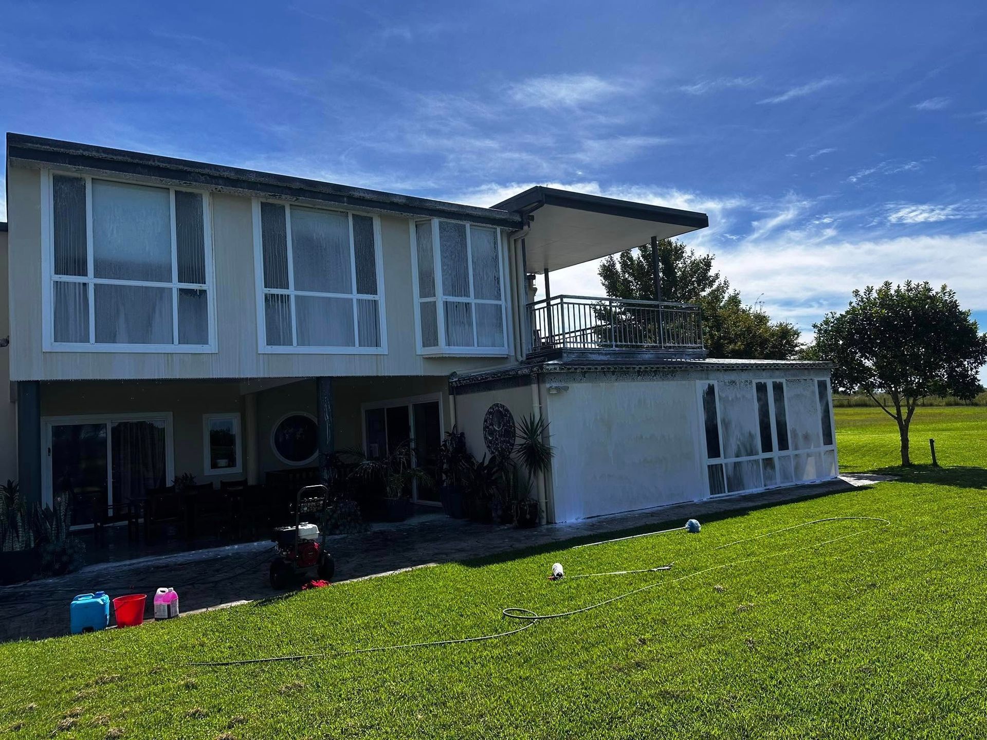 A large white house with a lot of windows is sitting on top of a lush green field — Lighthouse pressure washing in Thrumster, NSW