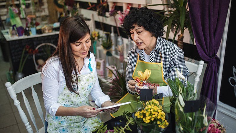 Older woman talking to younger woman next to flowers