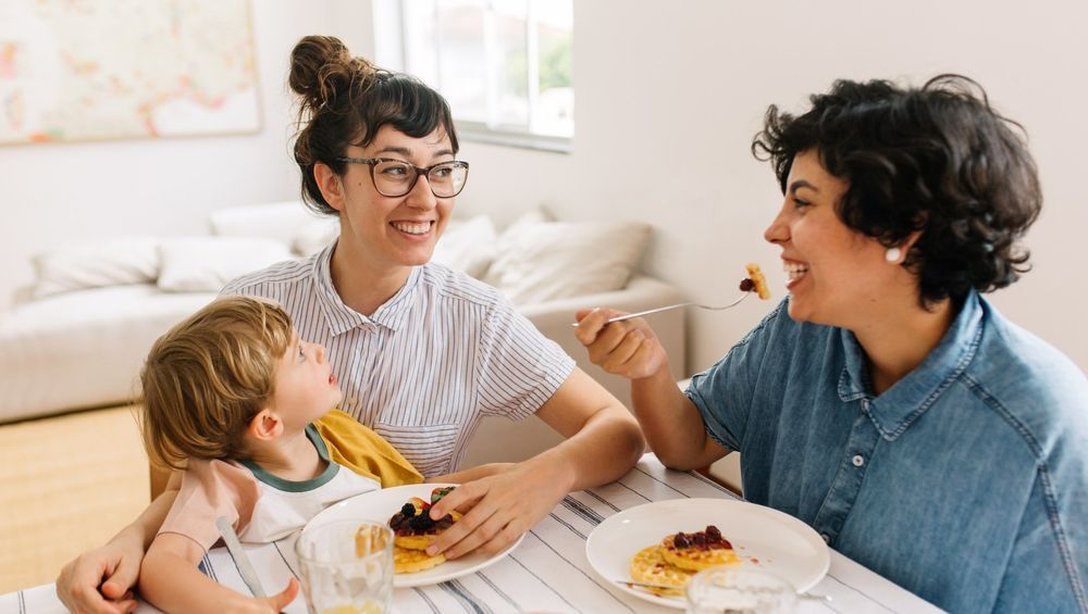 Two women and a child enjoy breakfast together at a table.