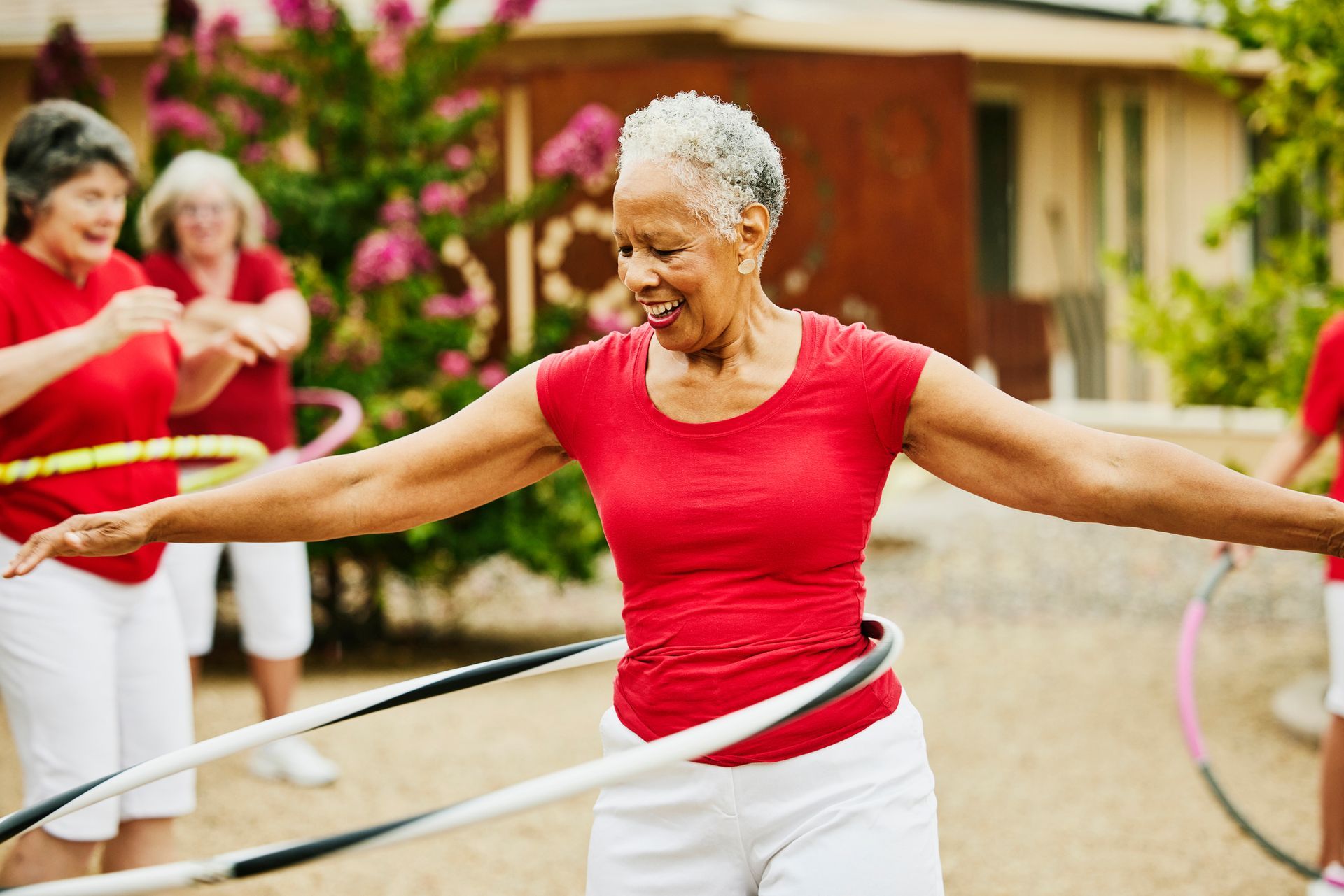 A group of older women are playing with hula hoops.