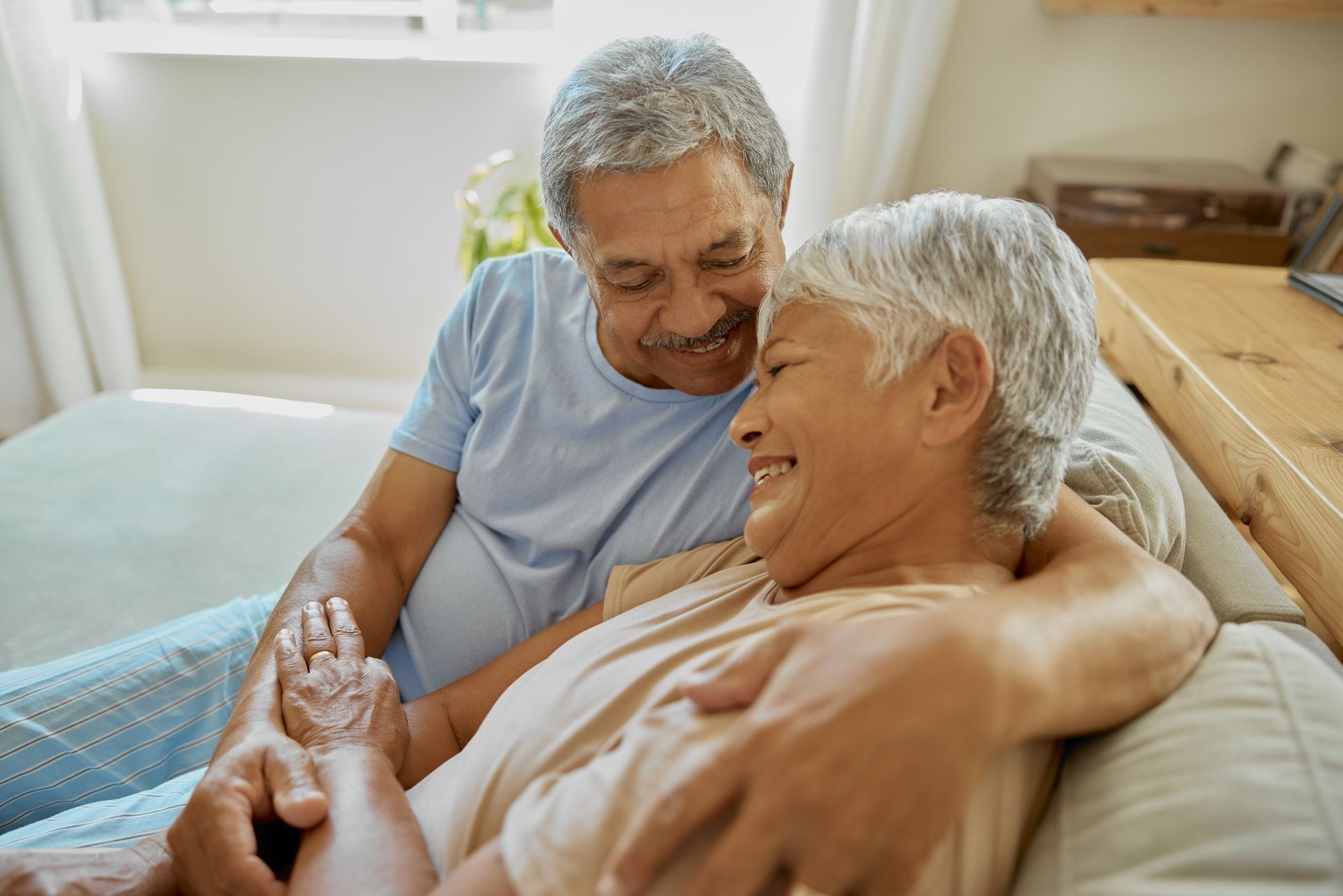 A happy senior couple on a sofa bond in their hospice care home.