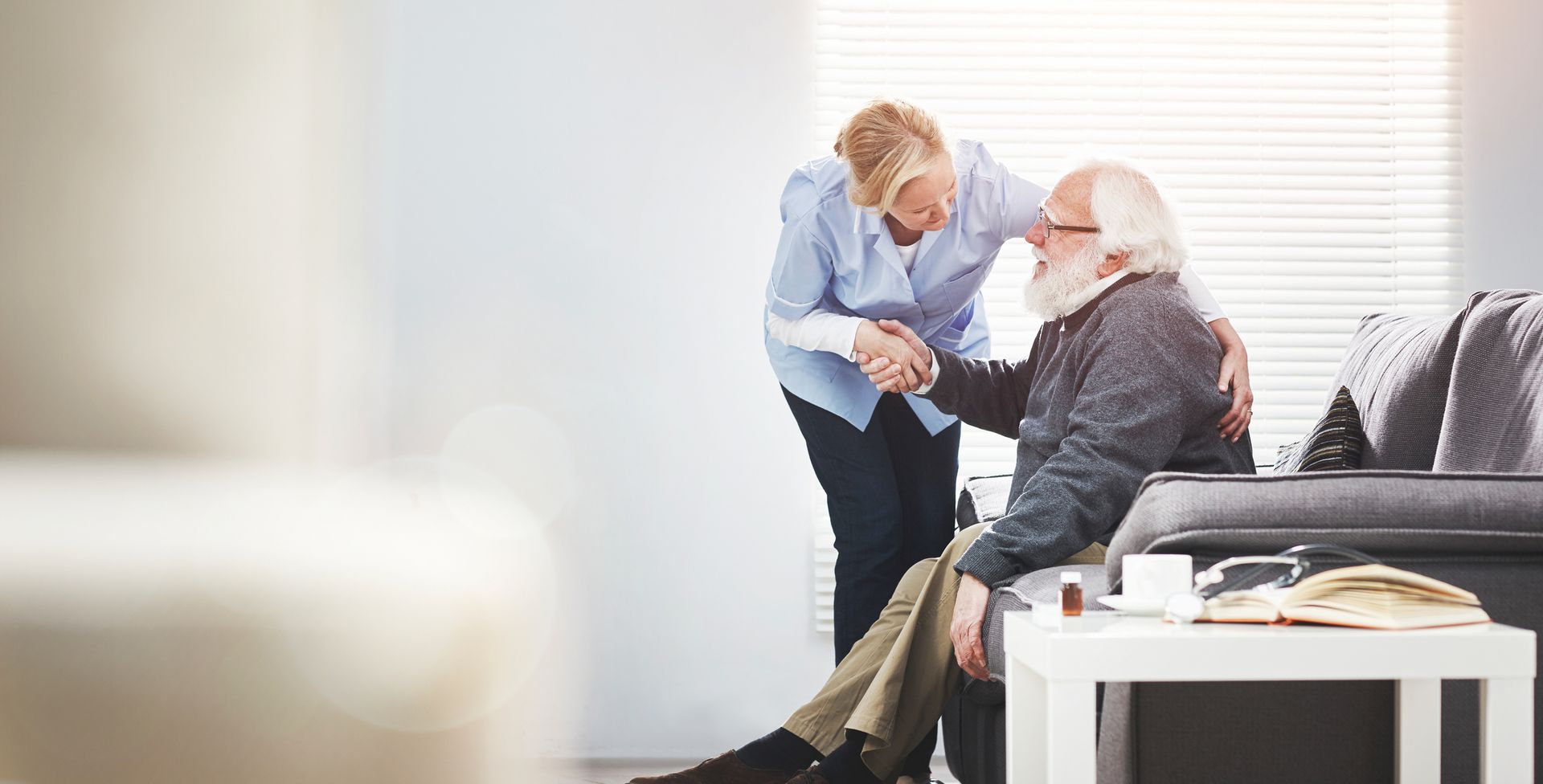 Hospice care provider assisting senior patient, who is reclining comfortably in a chair.
