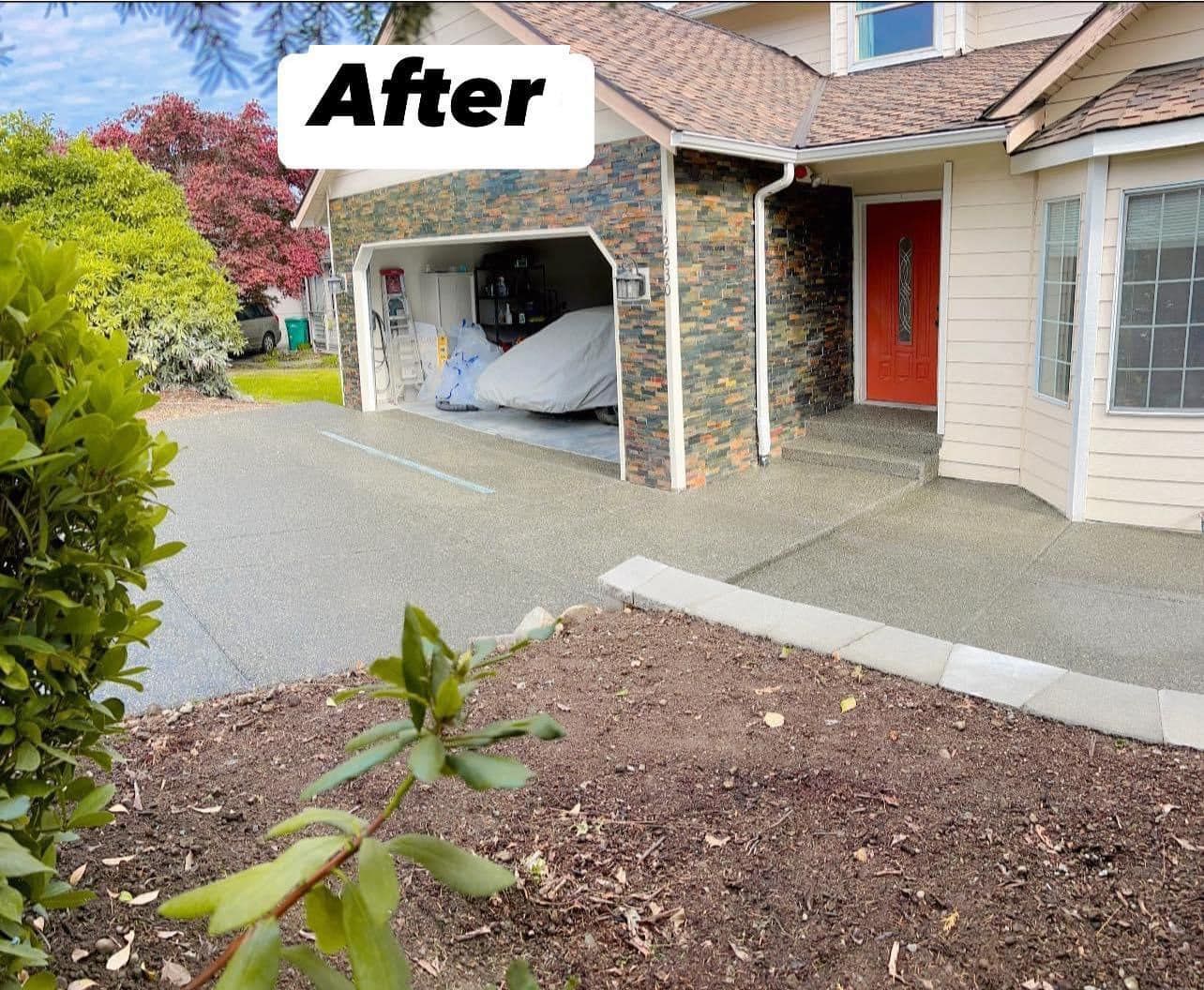 House exterior after renovation; stone garage, red door, fresh driveway, and landscaping.