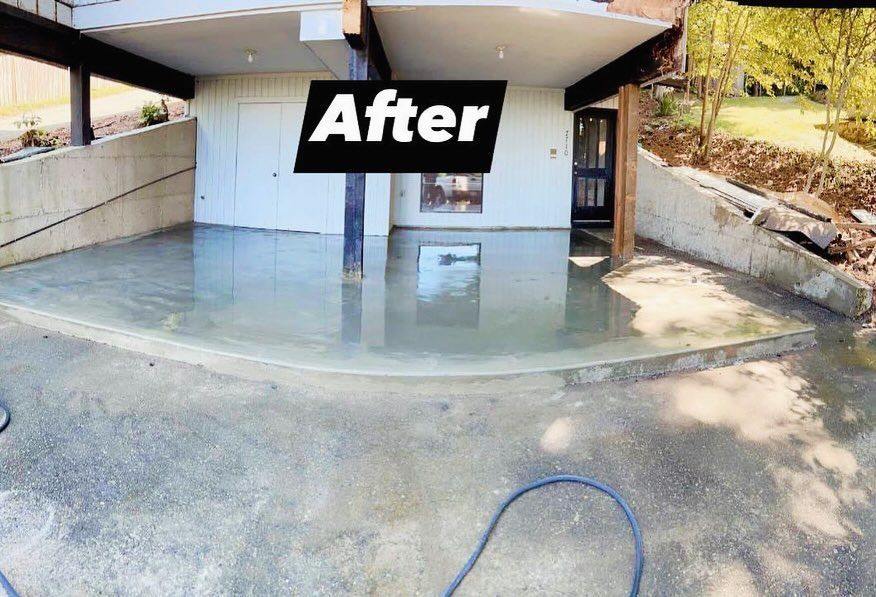 Newly poured concrete patio under a house with a retaining wall.