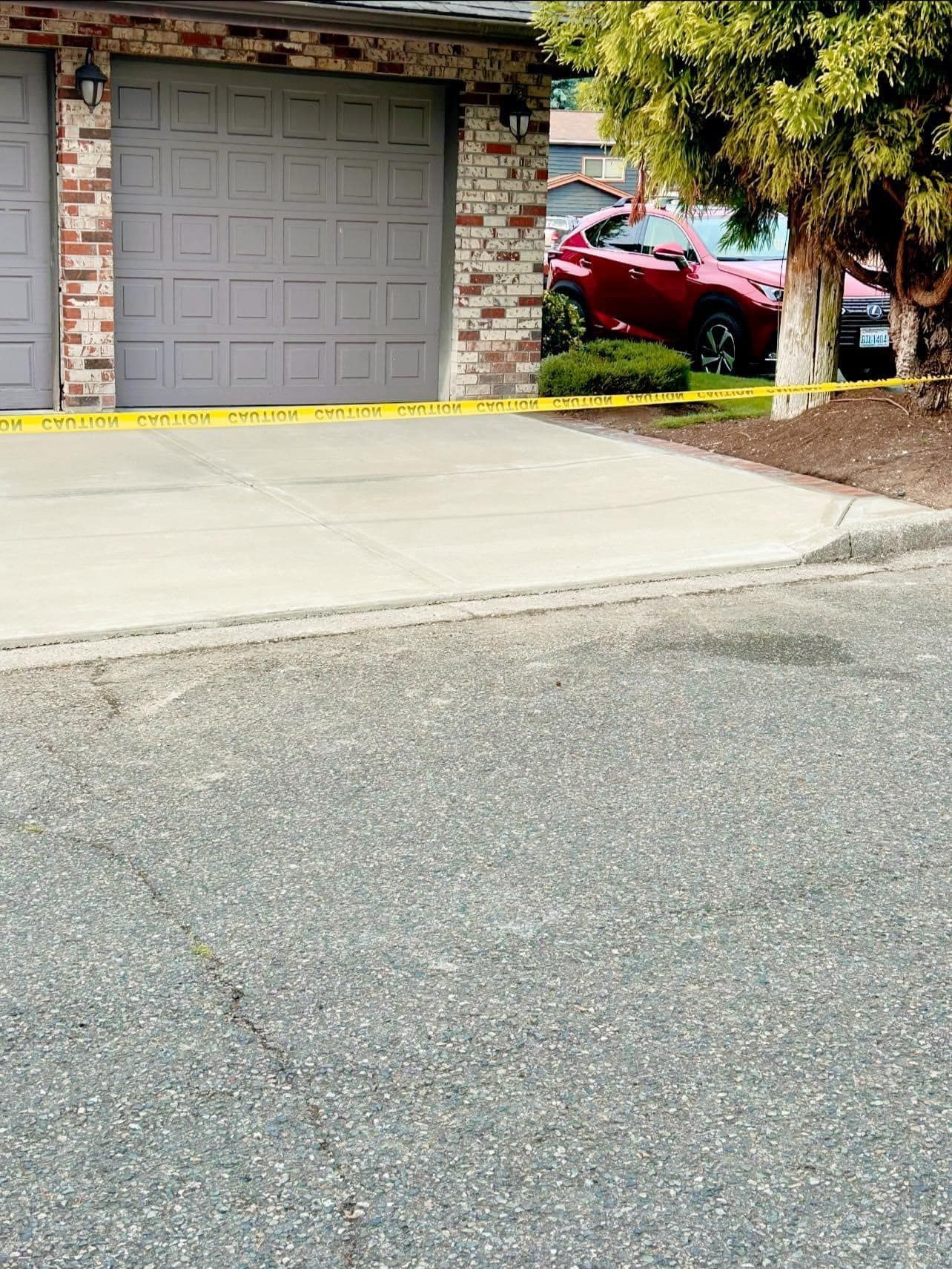 Garage with caution tape and red car parked behind it.