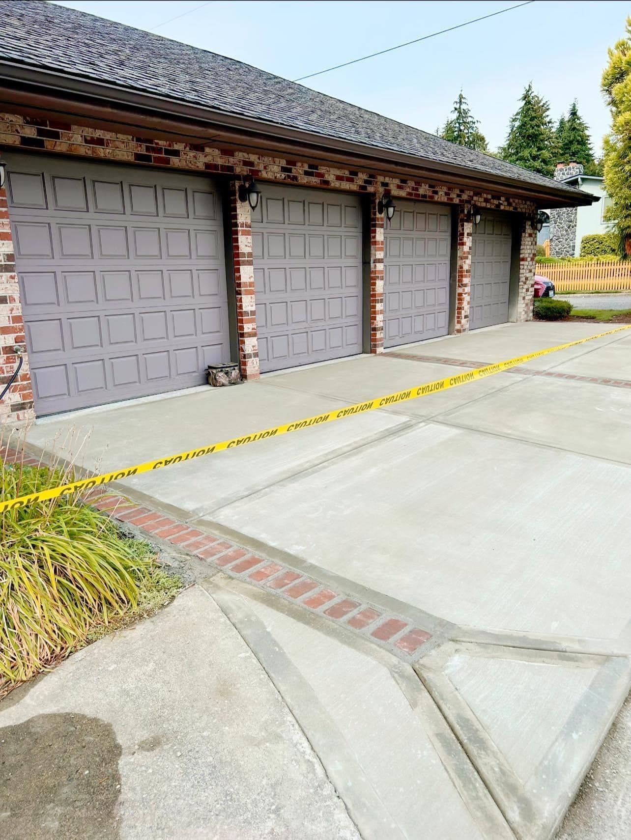 Garage doors with brick trim, marked off by caution tape. Concrete driveway.