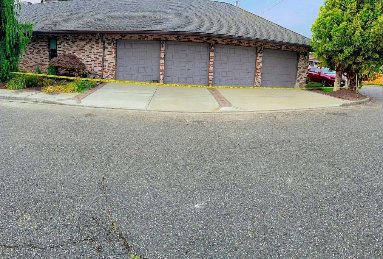 Garage with three gray doors, brick facade, and yellow caution tape across the front.
