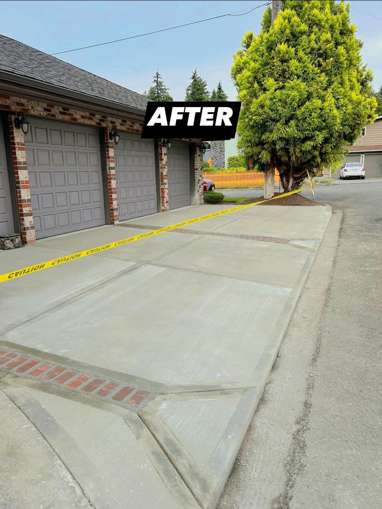 Newly poured concrete driveway with garage and tree in background.
