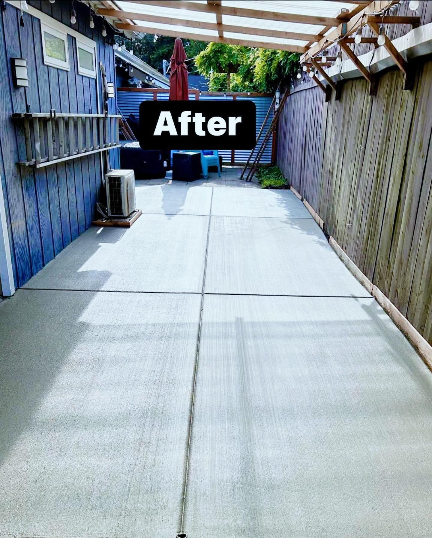 A narrow concrete patio with blue siding and a wooden fence;