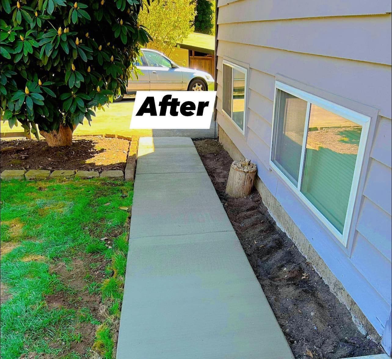 Newly poured concrete walkway next to a light purple house, with a tree and a car visible.