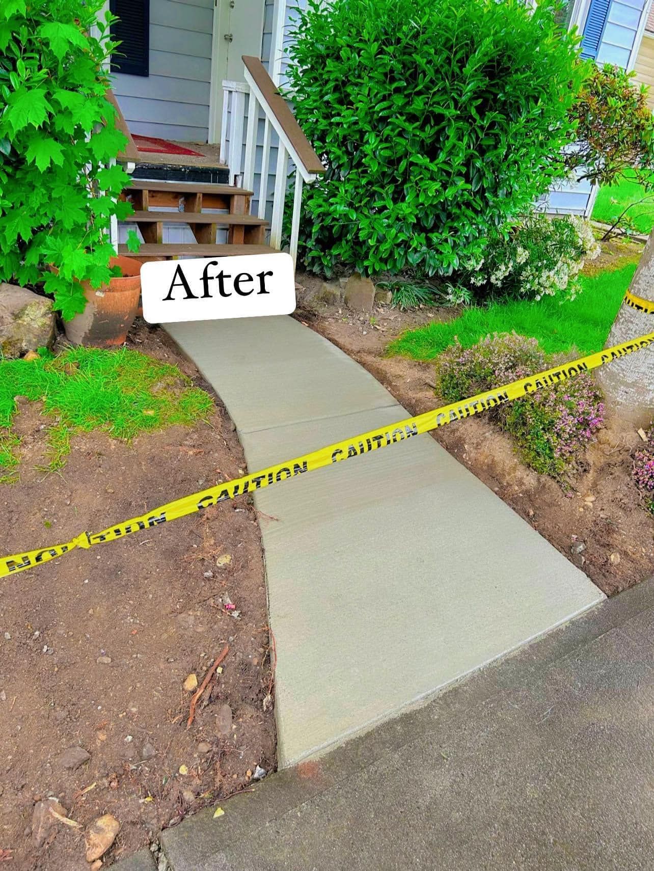 Newly poured concrete walkway leading to a house entrance, bordered by dirt, grass, and caution tape.