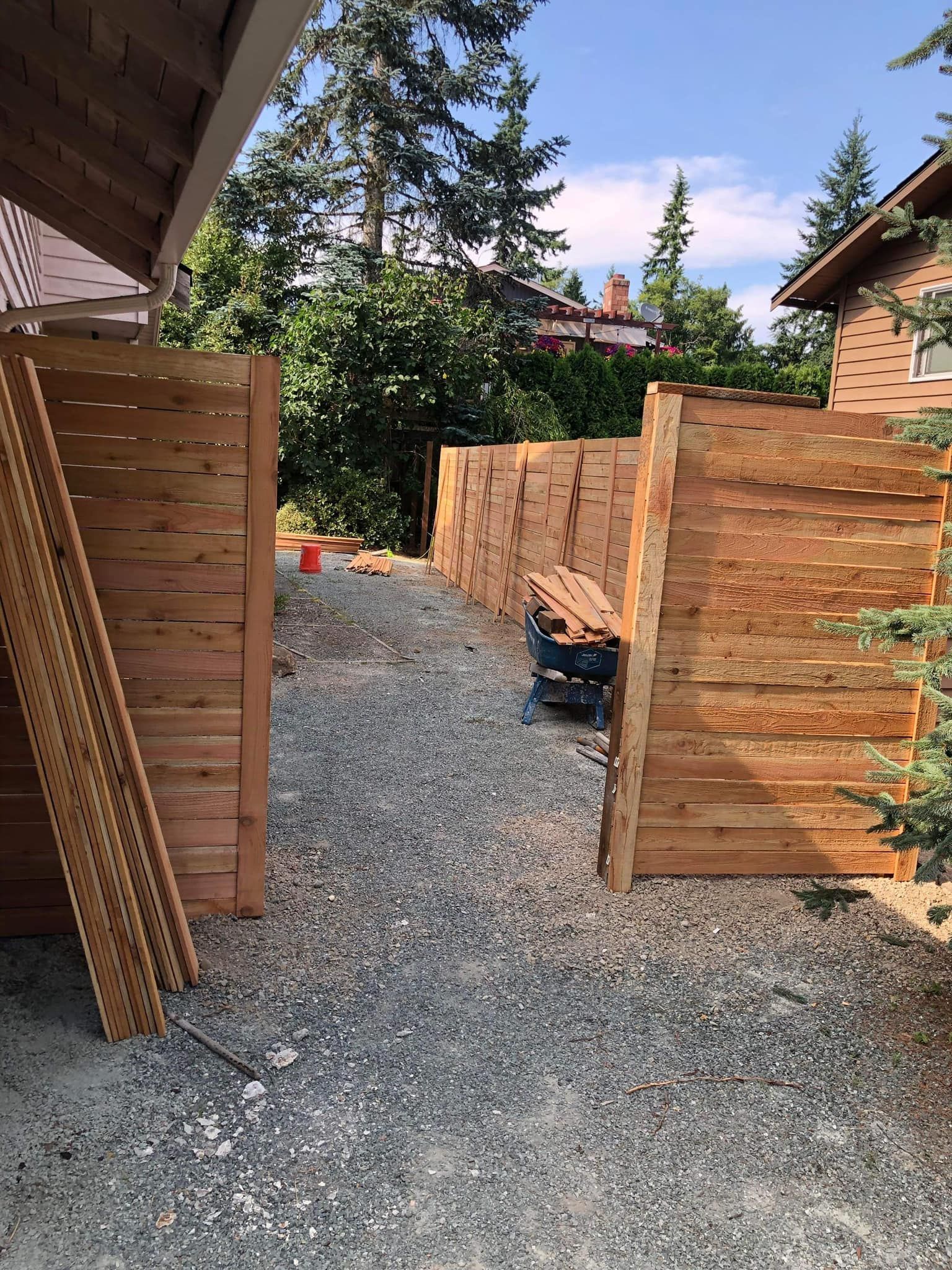 Wooden fence under construction with gravel path.