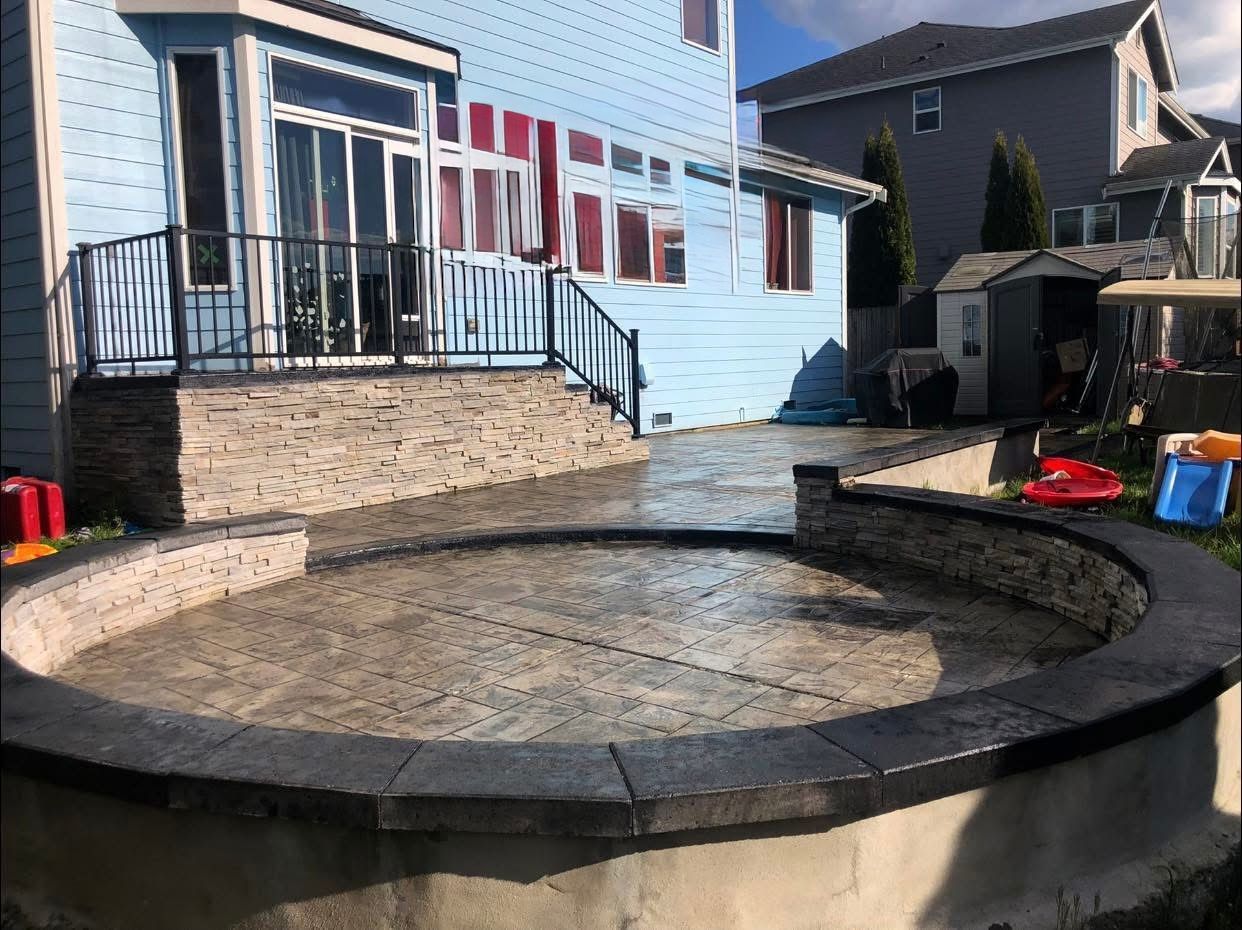Backyard patio with raised edges, stone facade, and blue house in the background.